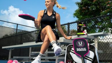 Anna Leigh Waters sitting on pickleball court bench holding paddle, Fila outfit, pink pickleball, and U by Kotex sponsorship gear.