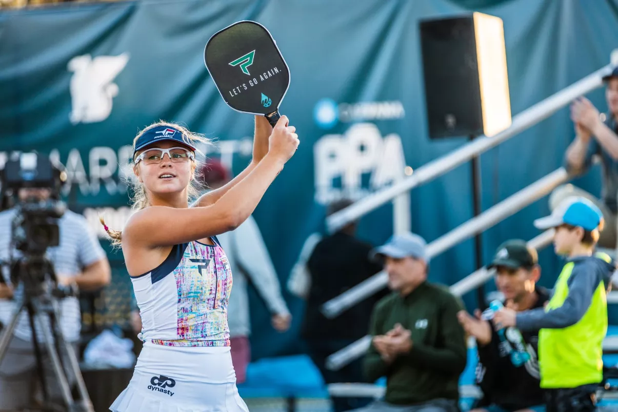 Anna Leigh Waters holding paddle on pickleball court during professional match, celebrating with crowd in background.