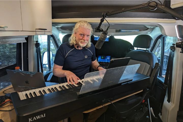 Dan Clancy, CEO of Twitch, playing a keyboard and speaking into a microphone during a casual livestream setup.