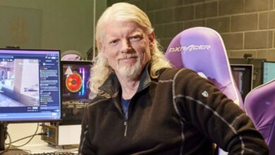 Twitch CEO Dan Clancy sitting in a gaming chair beside a computer setup with a live Twitch stream on screen.